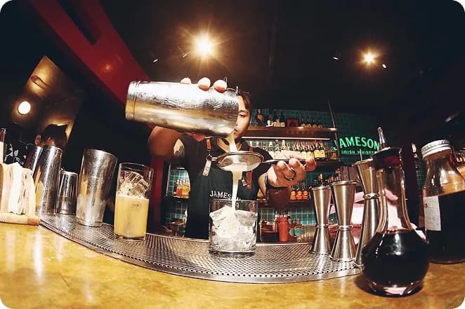 Cocktail being strained over ice behind the Kampai bar