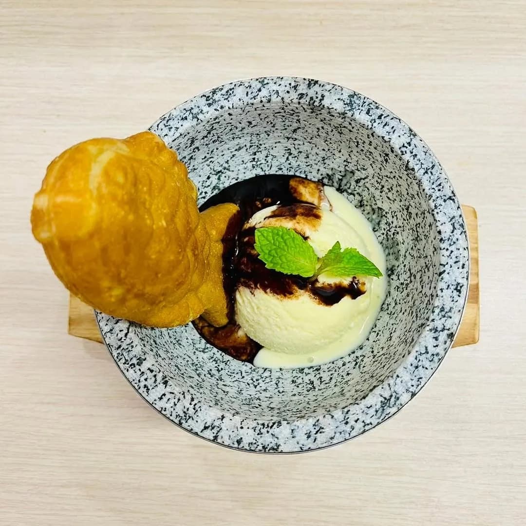 Fish-shaped pastry with vanilla ice cream on a patterned plate