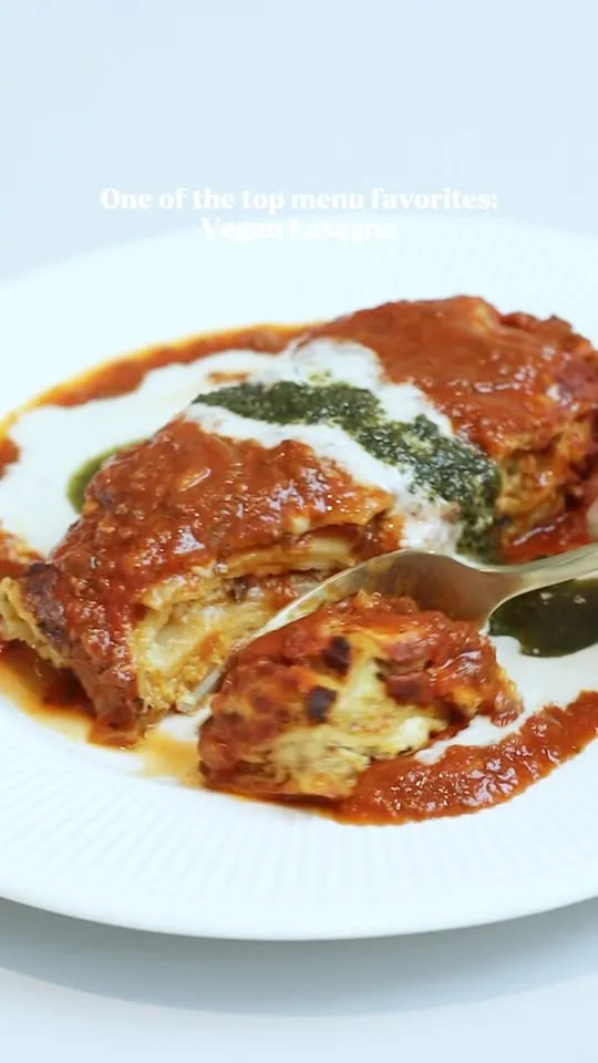 Vegan lasagna covered with tomato, white and green herb sauces