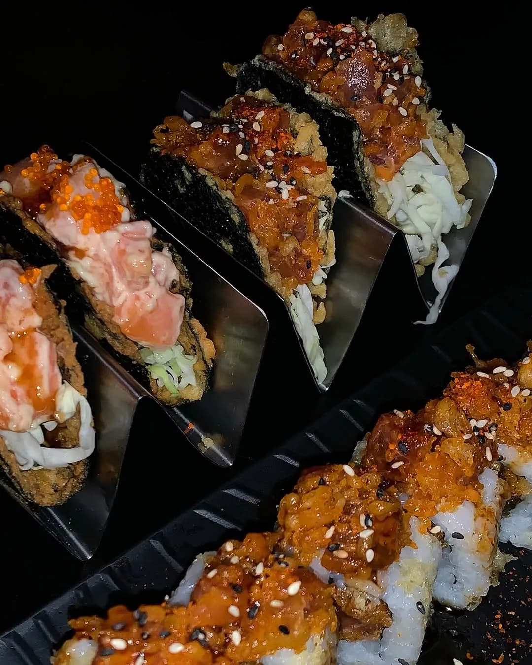 Assorted sushi rolls arranged on a black serving plate.