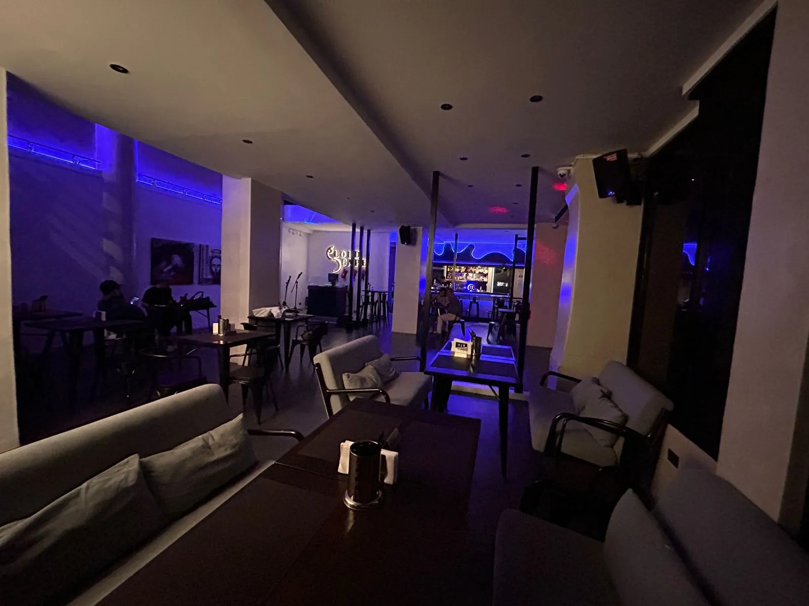 Dim lounge seating and bar lit in blue and violet at night