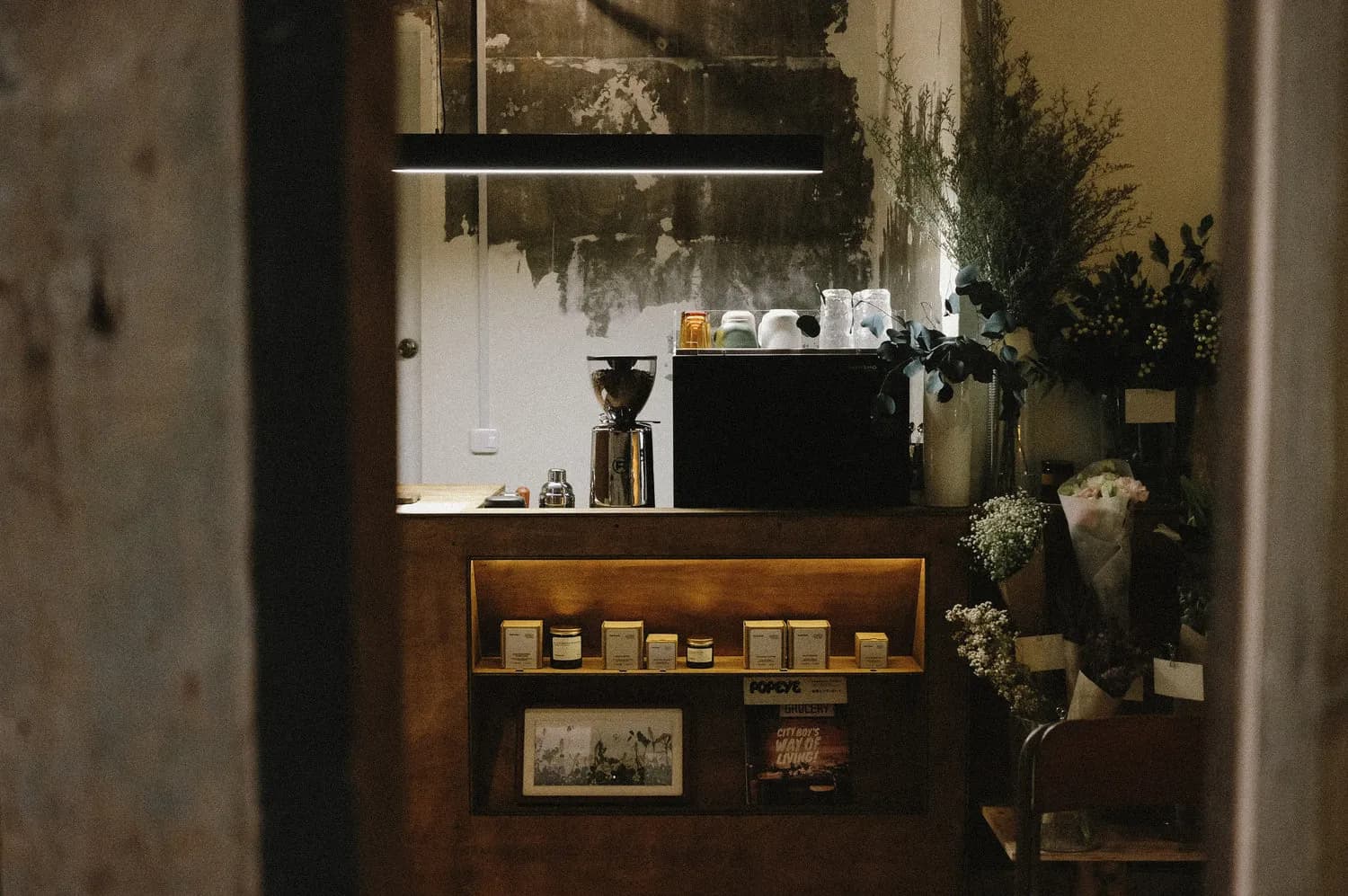 Wooden coffee counter framed by flowers and greenery