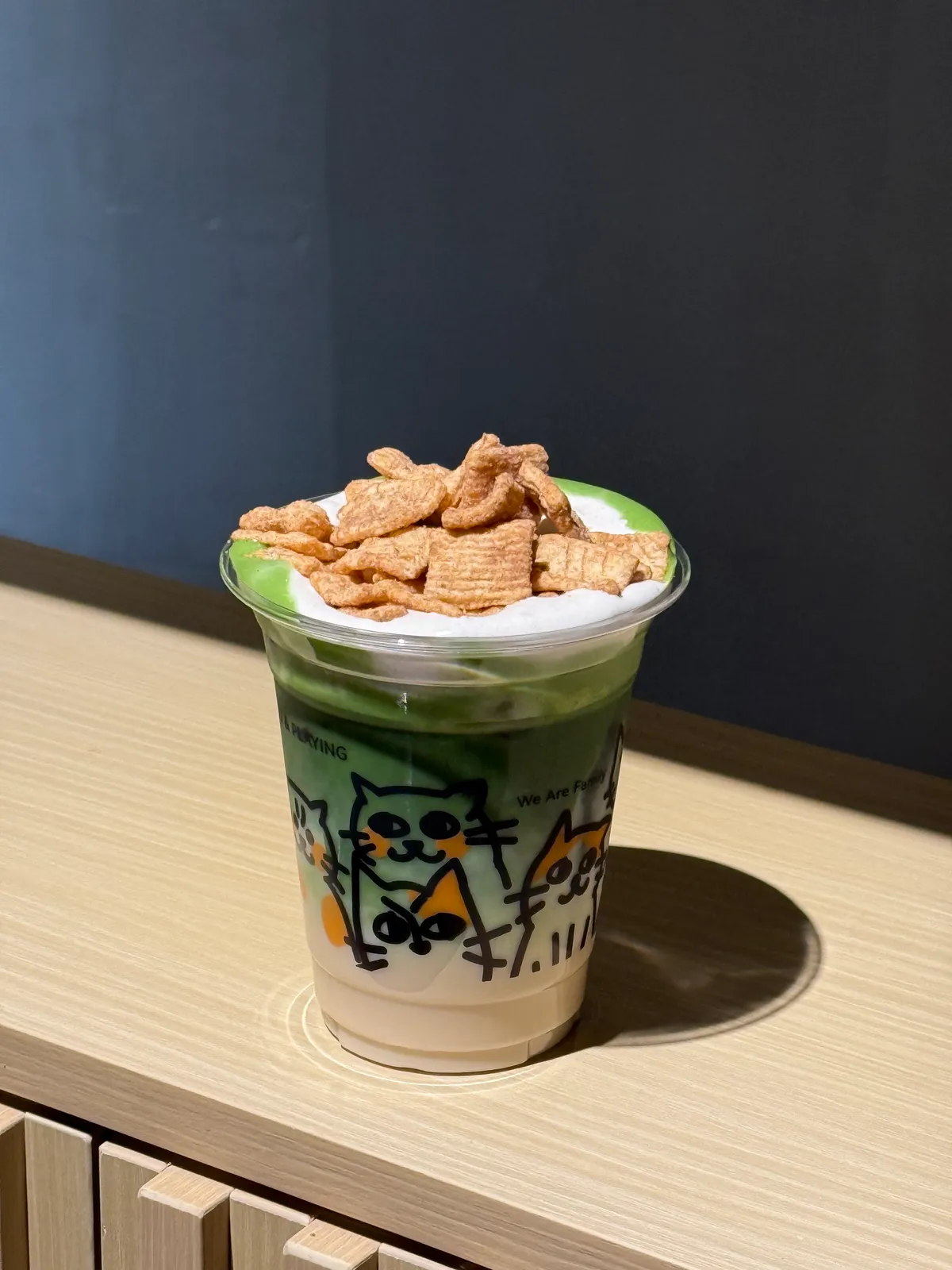 Layered iced matcha topped with cream and cereal pieces